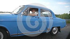 Classic old car traveling on highway on rainy summer day. Young couple driving on country road in vintage automobile