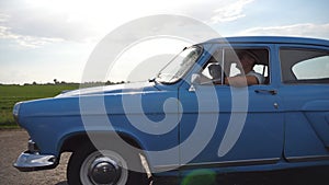 Classic old car traveling on highway on rainy summer day. Young couple driving on country road in vintage automobile