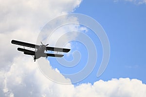 Classic old retro vintage airplane with a propeller in the sky on a background of clouds