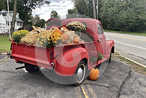 A classic old truck filled with Halloween season flowers hay and festive fall orange pumpkins
