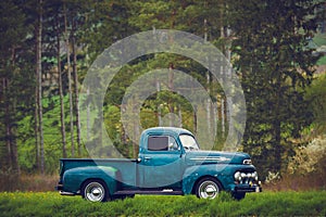 Classic oldtimer vintage American pick-up truck of the 1950s on a country road