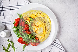 Classic omelet with cheese and tomatoes salad on white plate, top view