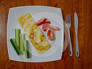 Classic omelet with tomatoes and cucumbers on the white plate.