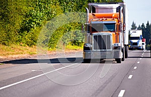 Classic orange semi truck reefer trailer on high way