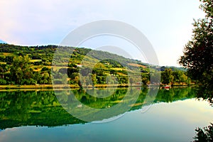 Classic panorama with Marche hilly landscape, emerald waters of the lake, tree silhouette and lush vegetation