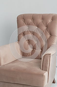 A classic pink armchair sits in a white room on a wooden floor. copy space