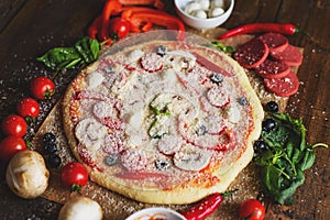 Classic pizza with vegetables and mushrooms with ingredients on a wooden table