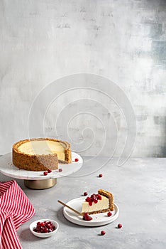 Classic plain New York Cheesecake on marble stand and a piece of it on the plate, side view. Copy space. Delicious dessert,