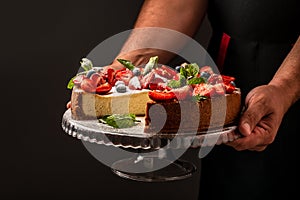 Classic plain New York Cheesecake sliced in the hands of the chef closeup view, banner menu recipe place for text