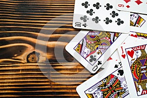 Classic playing cards on dark brown wooden table. Scattered cards.