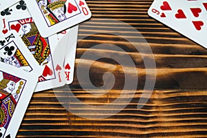 Classic playing cards on dark brown wooden table. Scattered cards.