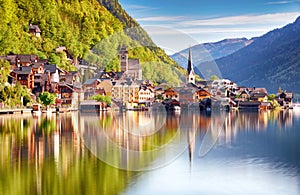 Classic postcard view of famous Hallstatt lakeside town reflecting in Hallstattersee lake in the Austrian Alps in scenic morning