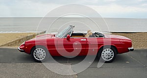 Classic Red Alpha Romeo Convertible Motor Car Parked on Seafront Promenade.