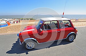 Classic Red Austin Mini Car parked on seafront promenade.