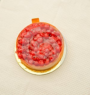 classic red berry curd tart on gold plate on table with copy space