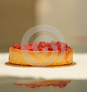 Classic red berry curd tart on gold plate on table with copy space