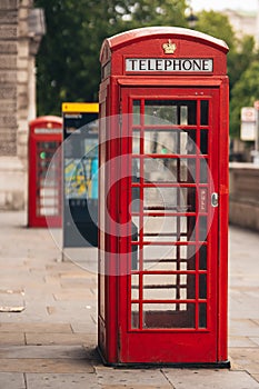 Classic red British telephone box in London with blurred background on hot sunny summer day