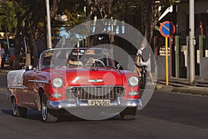 Classic red convertible automobile driving down a scenic route