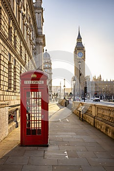 A classic, red telephone booth in front of the Big Ben clocktower in London