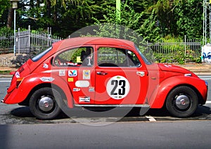 A red VW Beetle with the number 23 on the side parked on the street in Copenhagen, Denmark.