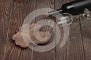 Classic red wine bottle with glass and plate under fruit on conceptual wooden tabletop background