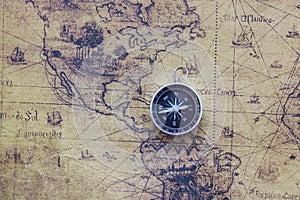 Classic round compass on background of old vintage map of world