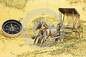 Classic round compass and bronze figurine with horses on background of old vintage map of world