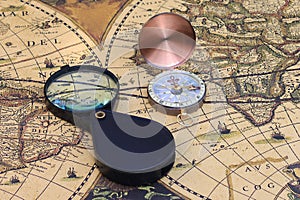 Classic round compass and magnifier on background of old vintage map of world