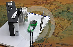 Classic round compass and old vintage camera on background of old vintage map of world