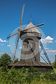 Classic Russian wooden windmill on rural landscape background