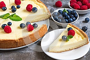 Classic sliced New York cheesecake with fresh berries and mint on stone background, close up