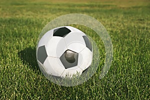 Classic soccer ball, typical black and white pattern, placed on the spot of stadium turf. Traditional football ball on the green