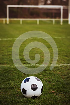 Classic soccer ball  with typical black and white pattern, placed on stadium turf. Traditional football ball on the green grass