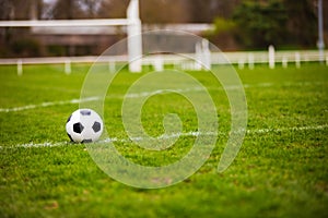 Classic soccer ball, typical black and white pattern, placed on stadium turf. Traditional football ball on the green grass lawn