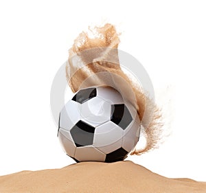 Classic sport football ball on sand pile over white background isolated. Sand splashing splatter by hitting soccer football ball