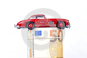 A classic sports car of the year 1954 of red color over euro bills isolated