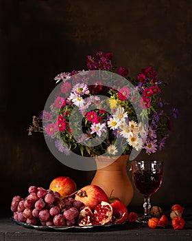 Classic still life with a bouquet of autumn flowers and ripe fruits