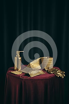 Classic still life with golden toilet paper, face mask and antiseptic for hands