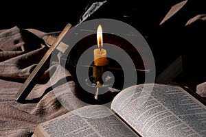 Classic Still Life with an Old Book, Holy Bible, Crucifix, and Lit Candle on a Wooden Table