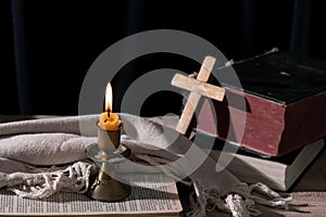 Classic Still Life with an Old Book, Holy Bible, Crucifix, and Lit Candle on a Wooden Table