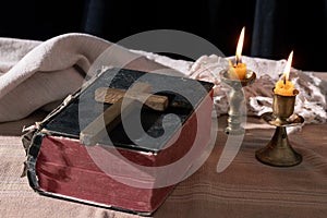 Classic Still Life with an Old Book, Holy Bible, Crucifix, and Lit Candle on a Wooden Table