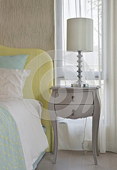 Classic style bedside table with reading lamp next to cozy style bedding