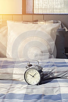 Classic style clock on checked pattern bedding with sunlight