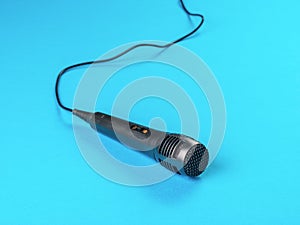 Classic stylish black wired microphone on a blue background