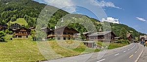 Classic swiss chalet in the middle of green alpine meadows . Cozy rural village Champery in Switzerland. Bright blue sky and white