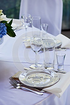 Classic table setting. Appliances, glasses, white tablecloth and plate photo