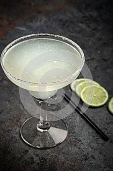 Classic tequila Margarita cocktail in a glass decorated with salt and lime on a stone