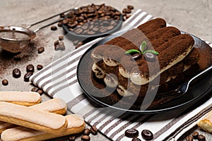 Classic tiramisu dessert and savoiardi cookies on ceramic plate on concrete background