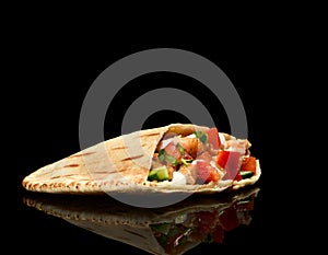 Classic tortilla wrap roll with grilled chicken or turkey and vegetables, tomato, lettuce with steam smoke on black