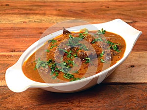 Classic Traditional Indian Lamb Dish, Mutton Rogan Josh served over a rustic wooden background, selective focus